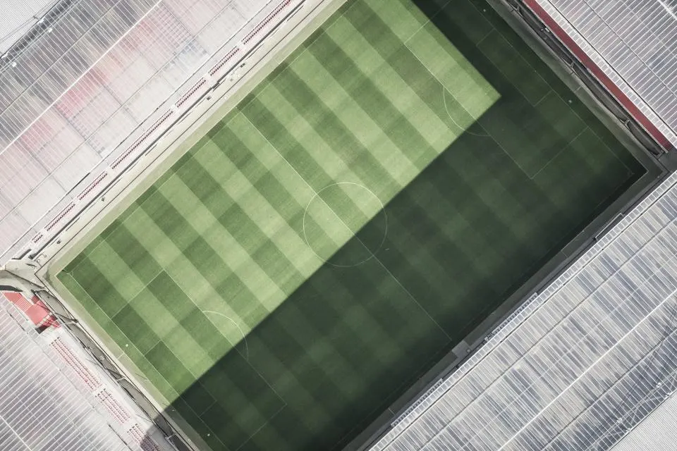 Vista cenital de un terreno de juego de hierba con franjas de siega y las gradas alrededor