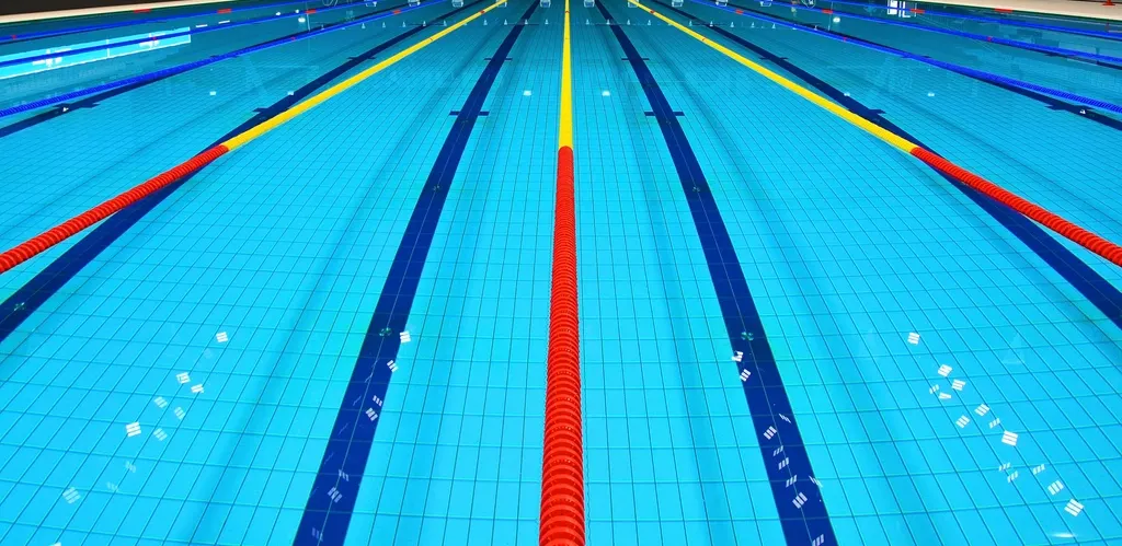 Piscina de competición vacía con corcheras de colores separando las calles