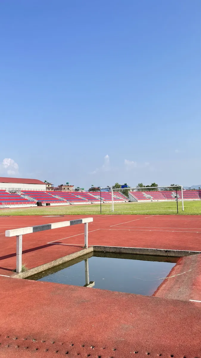 Foso de agua de obstáculos junto a la pista sintética de un estadio de atletismo con la grada al fondo