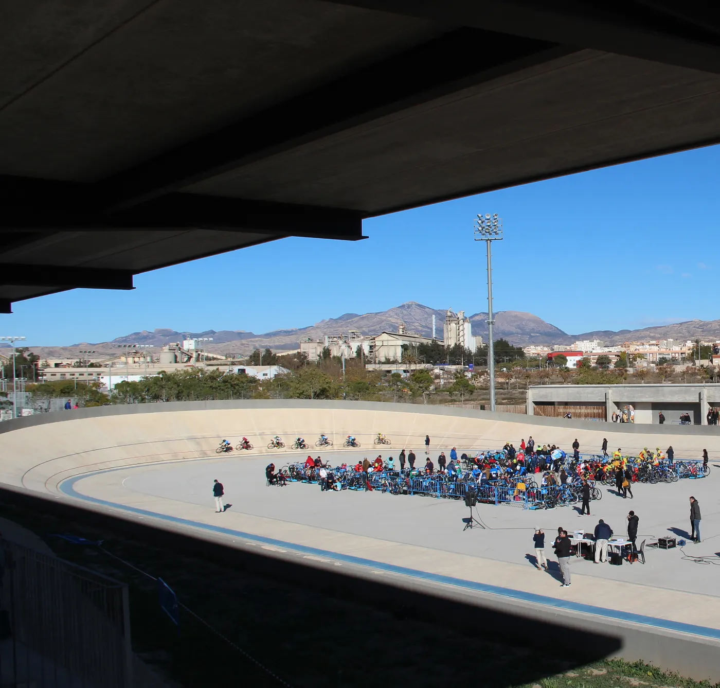 Anillo de velódromo al aire libre con fuerte peralte visto desde debajo de la cubierta de la tribuna